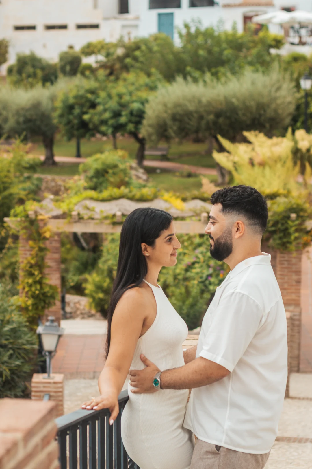 An intimate moment between a couple on a sun-drenched Mediterranean terrace, with a lush green garden backdrop typical of Andalusia's coastal landscape. An intimate moment between a couple on a sun-drenched Mediterranean terrace, with a lush green garden backdrop typical of Andalusia's coastal landscape.