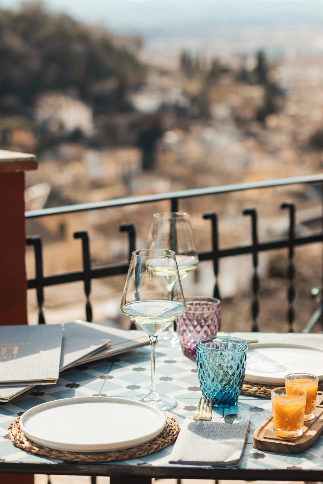A romantic table setting for two with chilled wine glasses on a sun-drenched terrace in the Albaicín district of Granada, capturing the golden hour atmosphere perfect for proposals and couples in Andalusia.