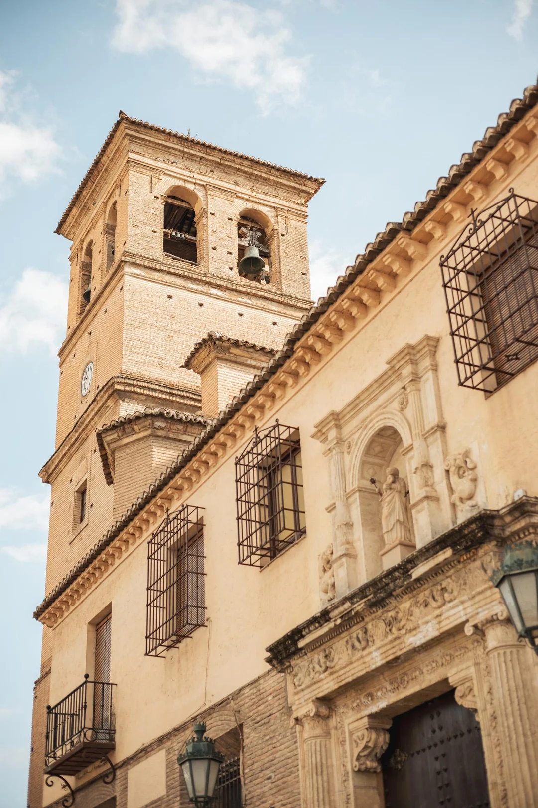 Low-angle view of the historic Iglesia de Santa Ana featuring intricate historical Andalusian architecture and a classic bell tower in the heart of Granada's Albaicín district.