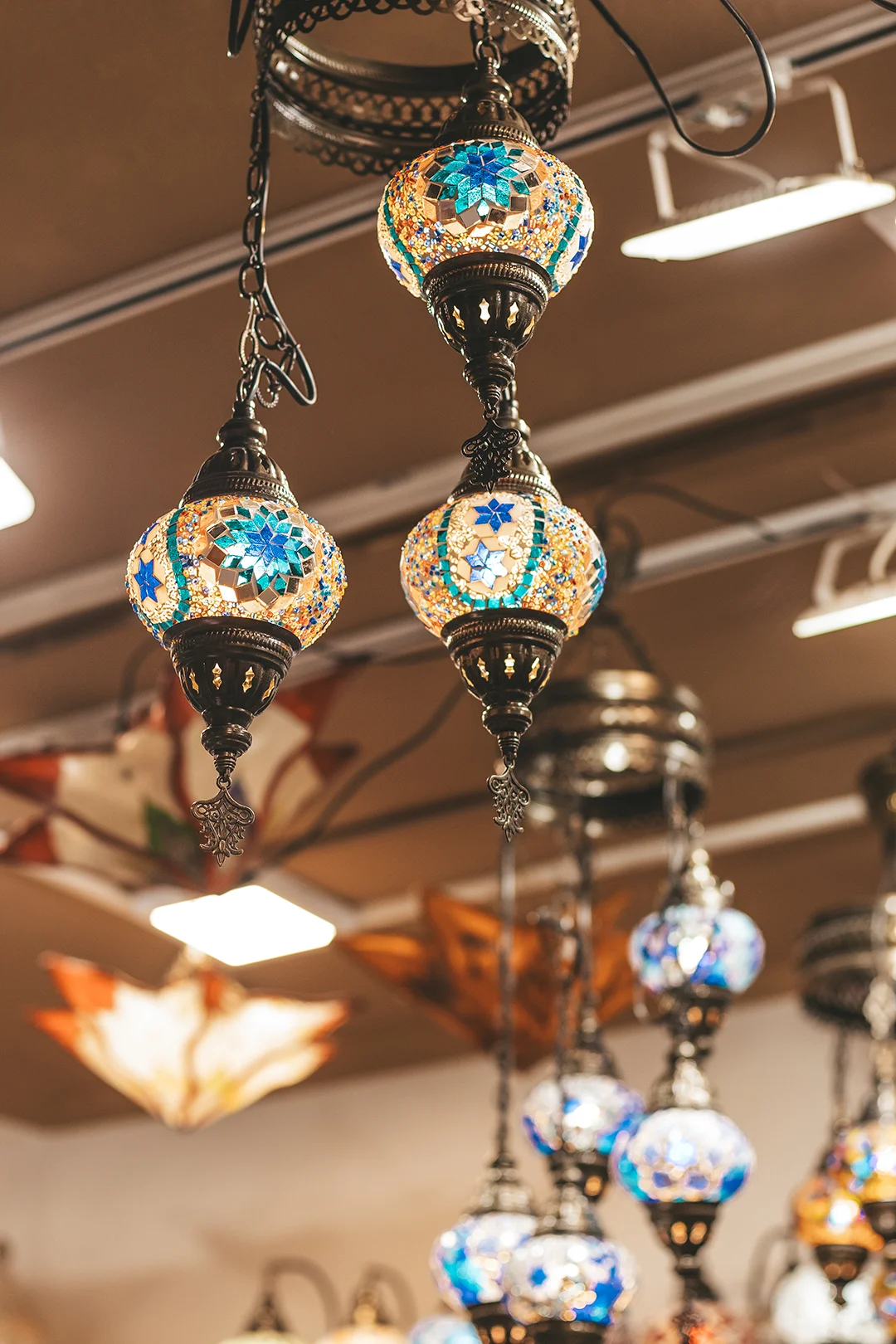 Intricate, glowing mosaic glass lamps hanging in a traditional shop, evoking the romantic atmosphere of historical Andalusian architecture found in the Albaicín district of Granada.