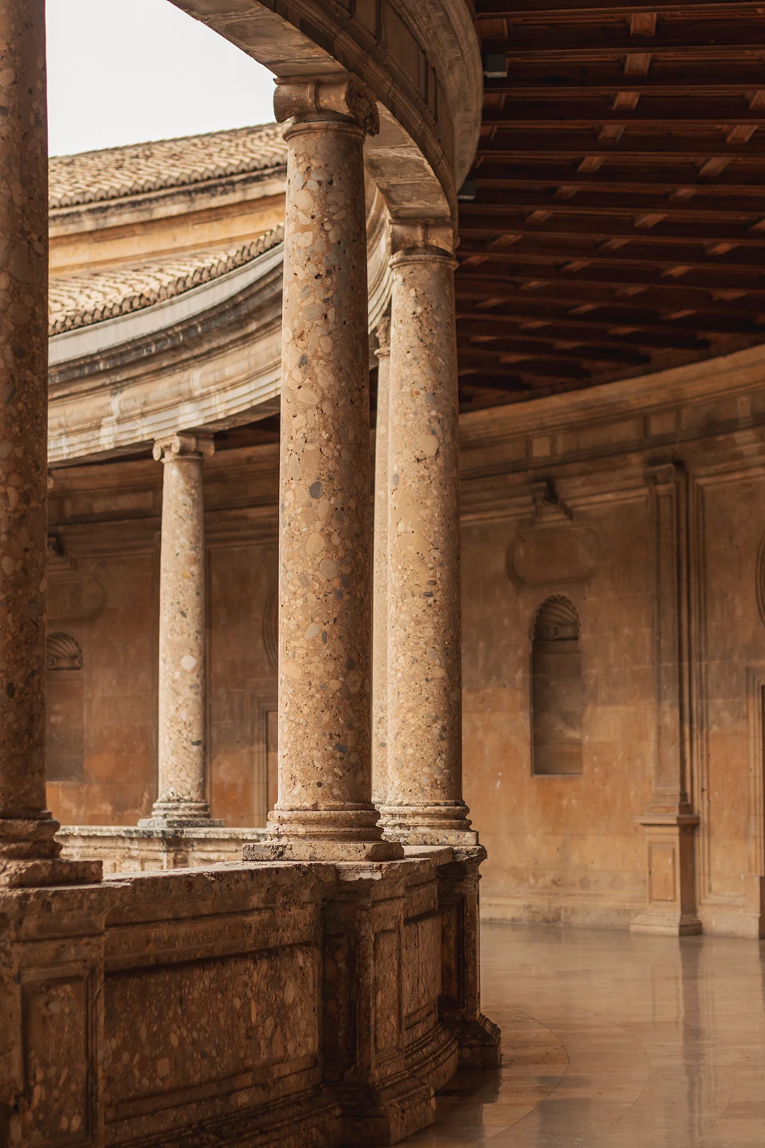 The magnificent Renaissance courtyard of the Palace of Charles V inside the Alhambra complex — its circular colonnade of marble columns is one of Granada's most stunning architectural settings.